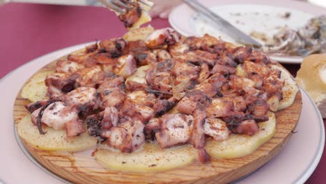 pulpo a la gallega served on a wooden plate with potatoes, paprika, and olive oil