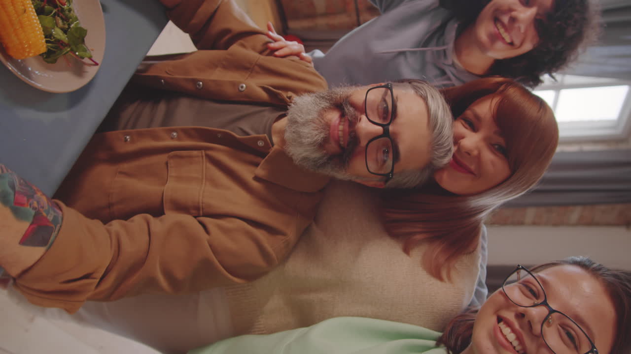 familia alegre sonriendo a la cámara mientras se toman selfies en la cena