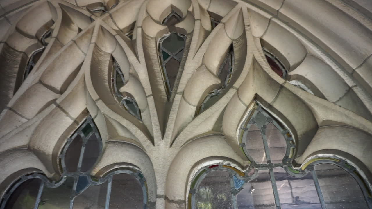 Camera pans over stonework tracery and leaded glass window