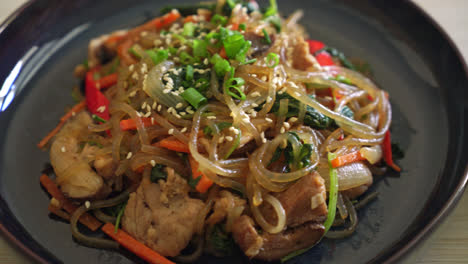 japchae or stir-fried korean vermicelli noodles with vegetables and pork topped with white sesame - korean traditional food style