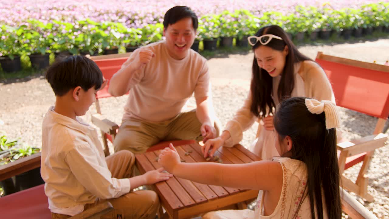 夏の屋外カフェでボードゲームをしながら楽しんでいる、楽しそうな親と子供たち