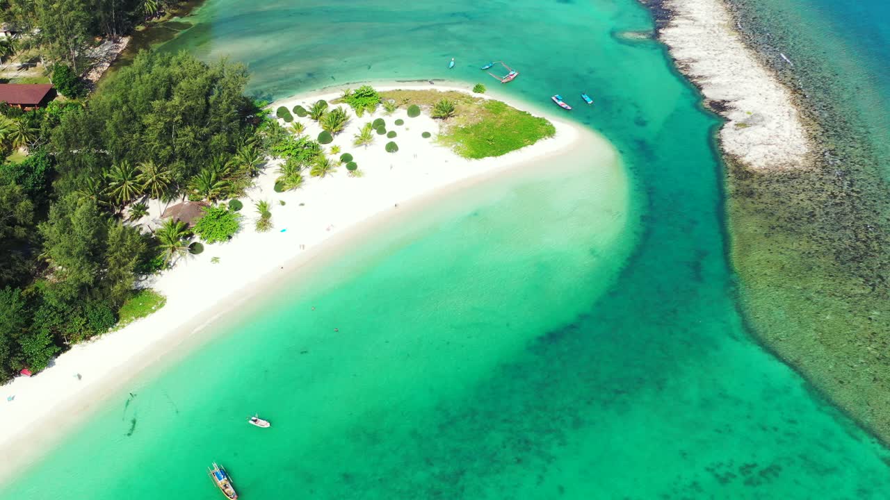Beautiful colorful patterns of turquoise lagoon and white sandy beach on shoreline of tropical island with lush vegetation, Thailand