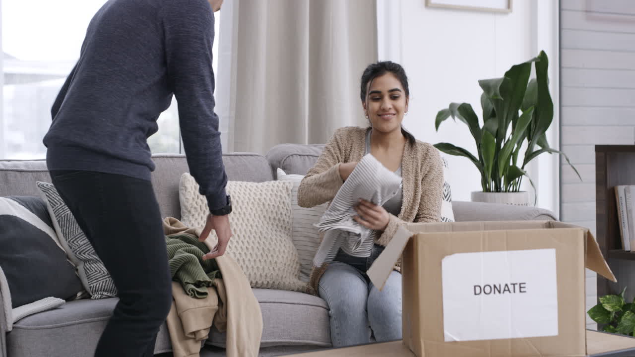 una joven pareja ordenando ropa mientras está sentada