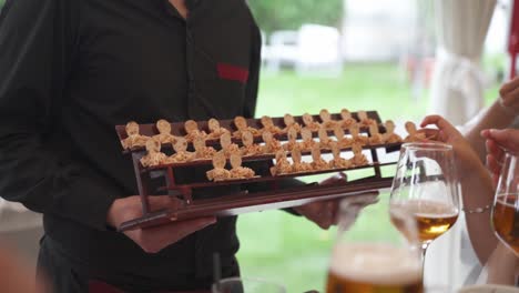 server in black uniform offering deserts to guests of an outdoor event