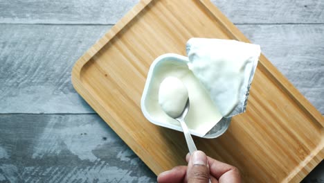 close-up of a person eating yogurt from a single serving container