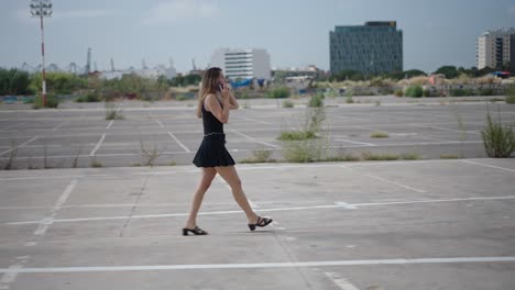 woman walking and talking on phone in empty parking lot