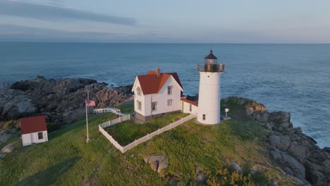 aerial drone shot of york beach maine flying around cape neddick nubble lighthouse at sunset