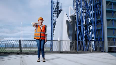 full body of asian female engineer with safety helmet showing thumbs down gesture and shaking her head while standing with space shuttle