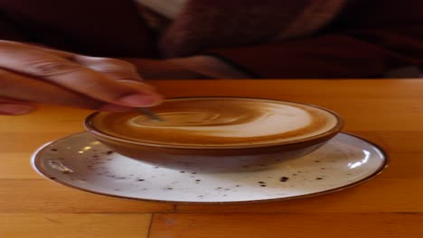 a person stirs their latte art coffee