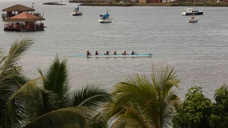 group of people canoeing on the tahitian sea with yachts in the background