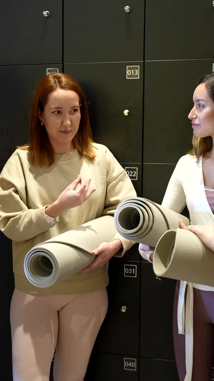 Femmes souriantes avec des tapis de yoga discutant dans un vestiaire