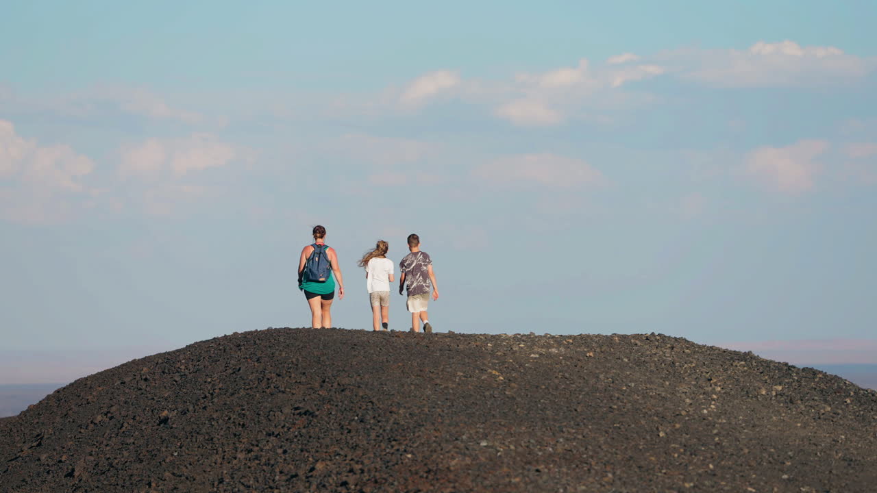 Family hiking on a rocky volcanic hill under a blue sky