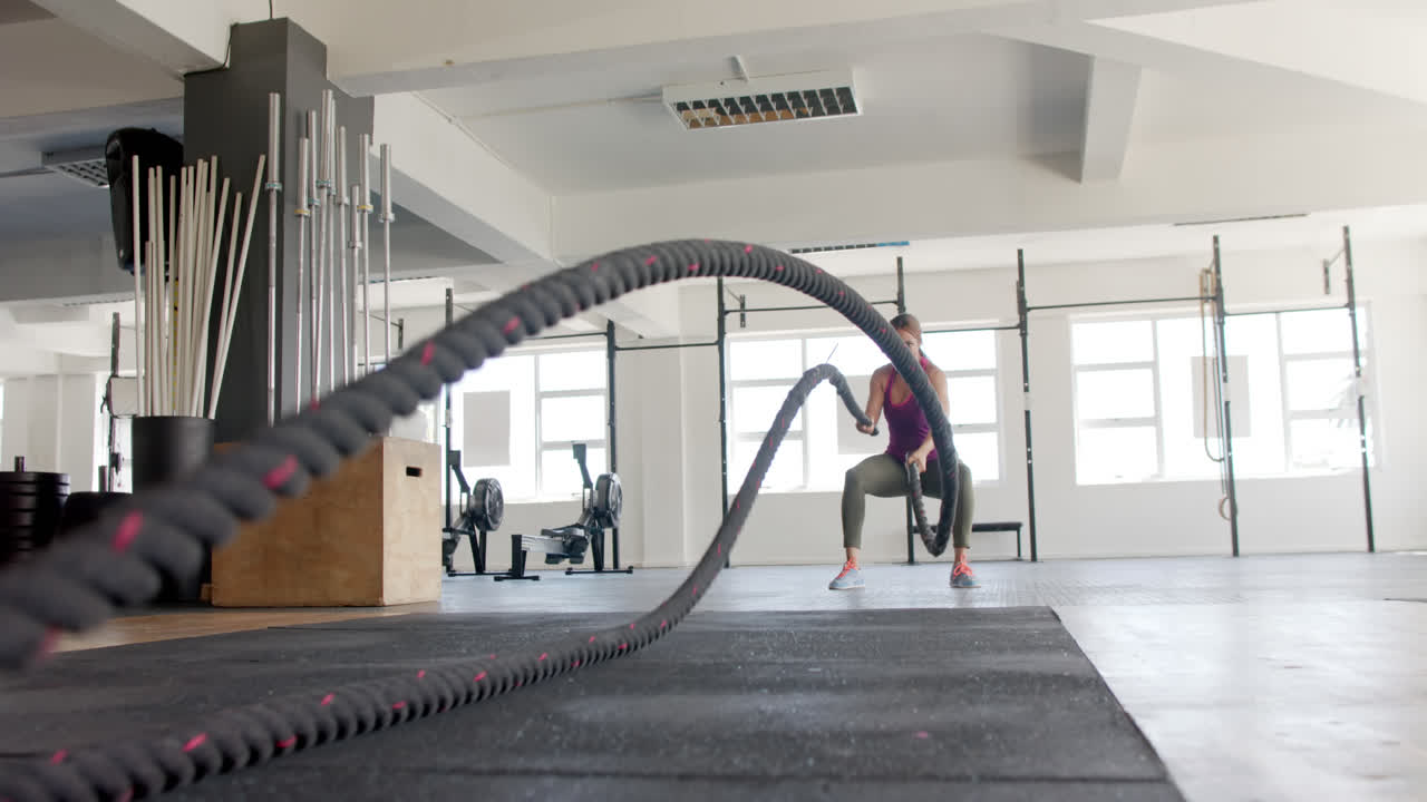 바뀌지 않은 두 인종의 여성이 체육관에서 로프와 싸우는 운동에 초점을 맞추고, 느린 동작으로