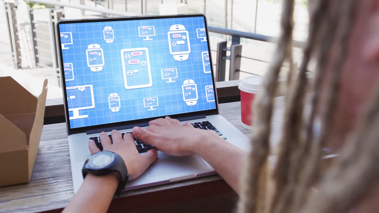 un hombre de negocios biracial con dreadlocks usando una computadora portátil para un chat digital en la oficina.