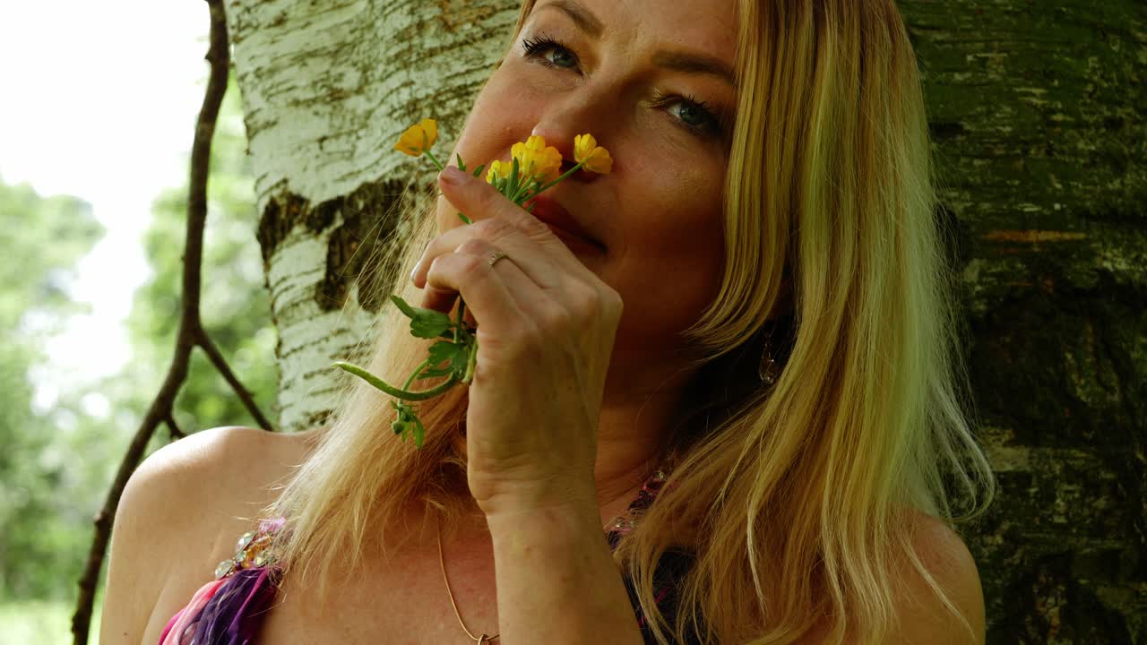 mujer atractiva y despreocupada que sostiene flores silvestres de mantequilla retrato en close-up 4k cámara lenta