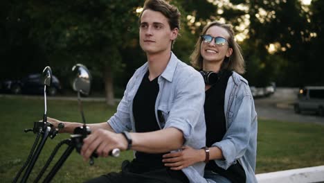 Joven-Apuesto-Con-Su-Bella-Novia-Montando-En-Bicicleta-En-La-Carretera-Del-Parque