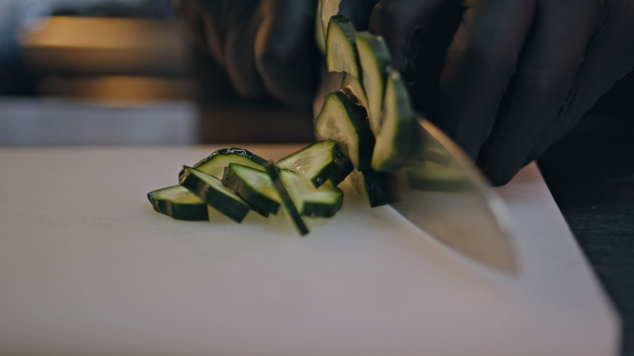Chef hands chopping cucumber in restaurant kitchen closeup. Unknown cuisine