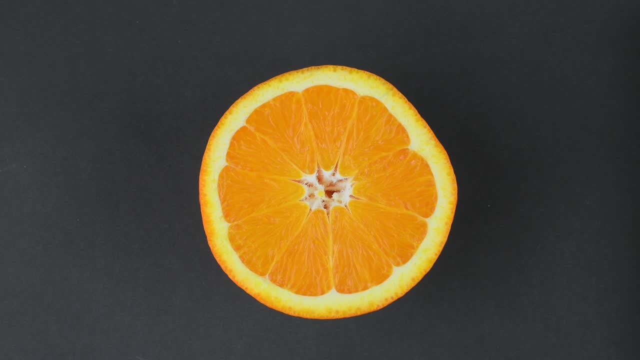 naranja en una sección de cerca. naranja bien iluminada gira alrededor de sí misma en un fondo negro. naranjas cítricos brillantes en un fondo negra. de cerca. cítricos frescos en un bucle de fondo negro. resolución de 4 k