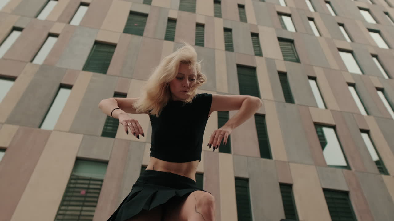 Ung kvinde danser udtryksfuldt foran en moderne bygning