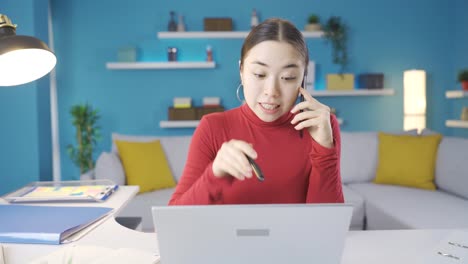 asian woman working from home also happily chatting on the phone in a good mood.