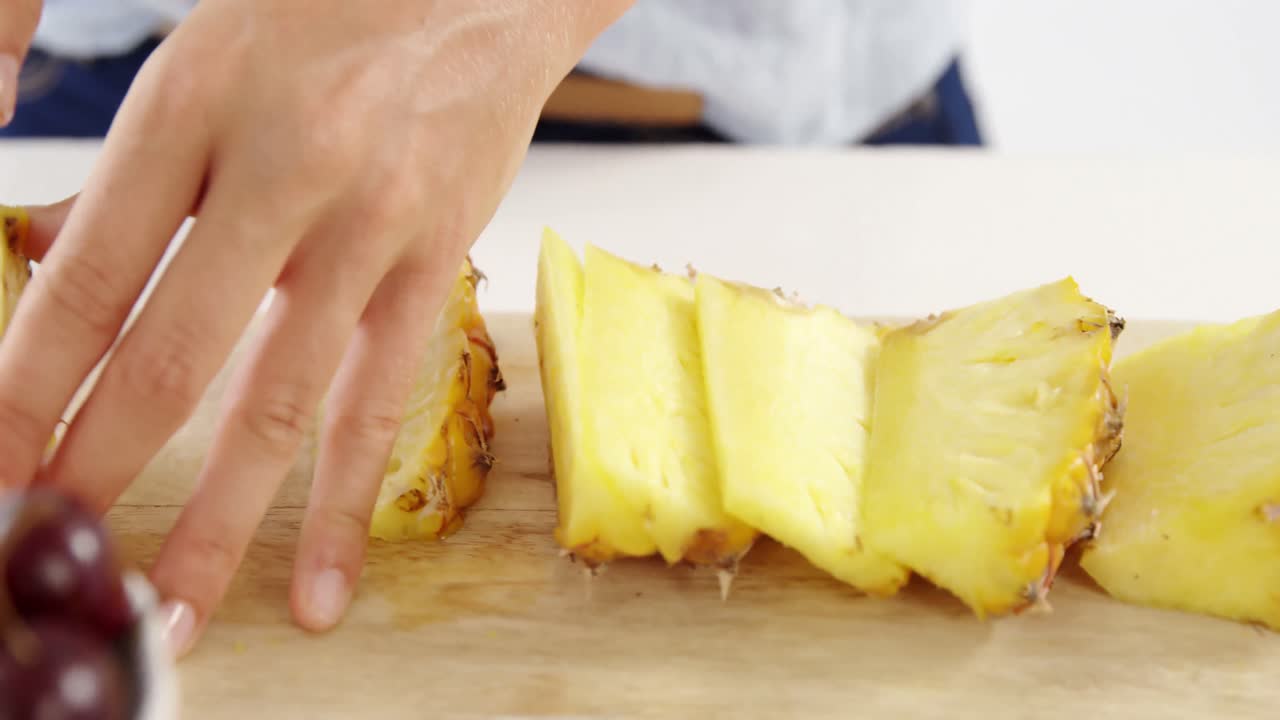 여자 가 자르는 보드 에 파인애플 을 자르고 있다