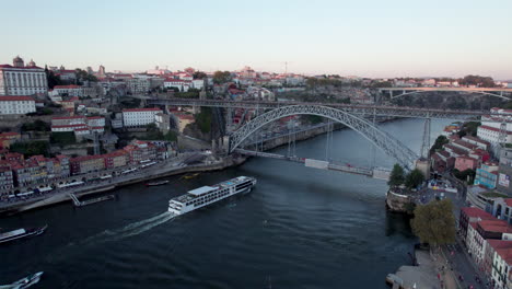 aerial view of sightseeing boat going under bridge in porto, portugal