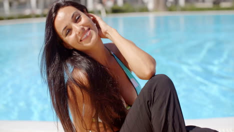 Sonriente-Mujer-Joven-Y-Bonita-Sentada-Junto-A-La-Piscina