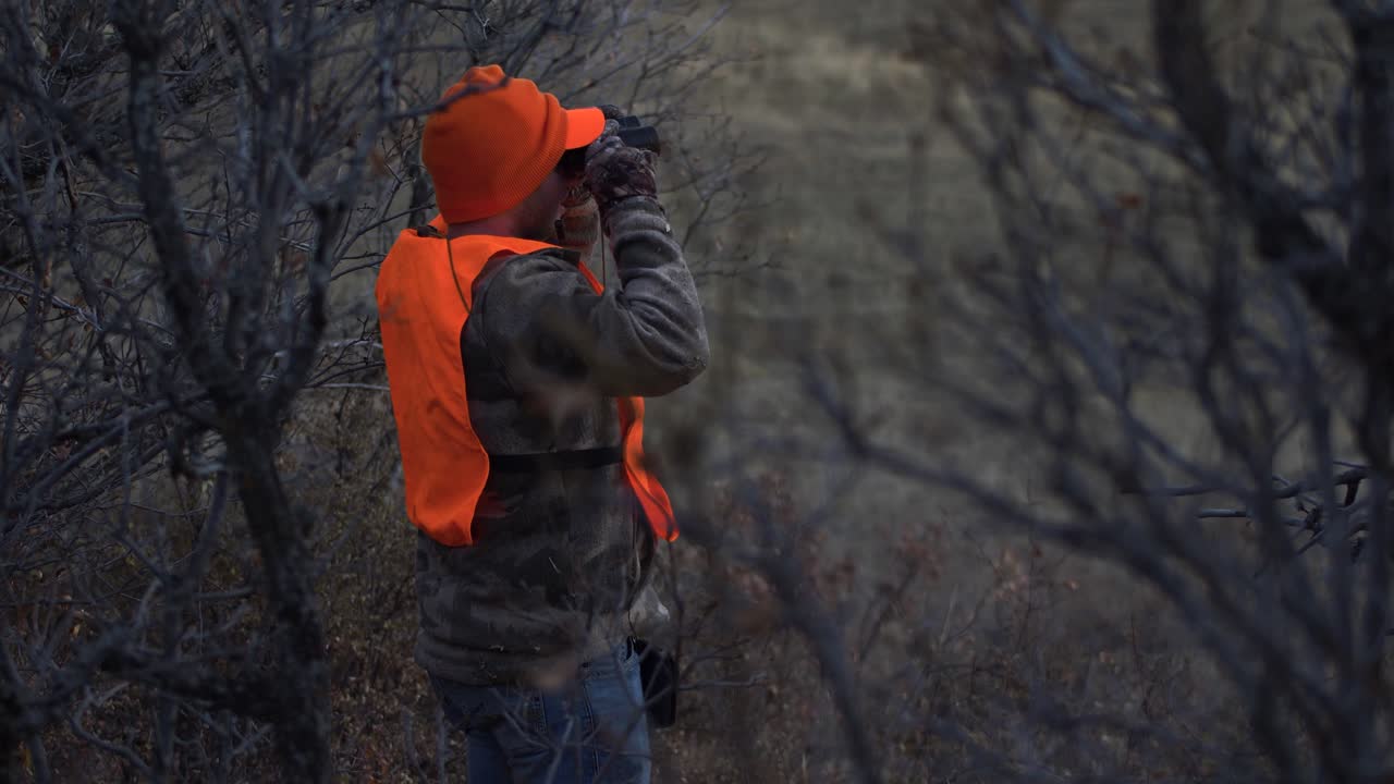 Hunter Stands and Looks through Binoculars. Handheld 4K