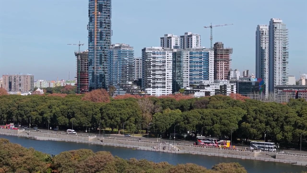Gli stagni della riserva ecologica di Puerto Madero e la vegetazione circostante con alti grattacieli per uffici sullo sfondo. Transizione aerea con inclinazione verso l'alto in un pomeriggio luminoso.