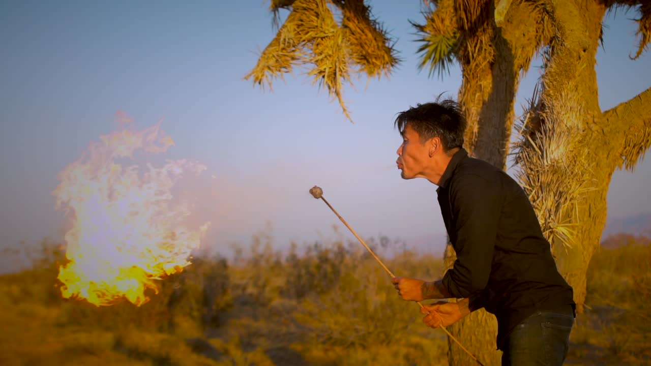 문신된 아시아인 남자가 사막에서 불을 피우고 있습니다.