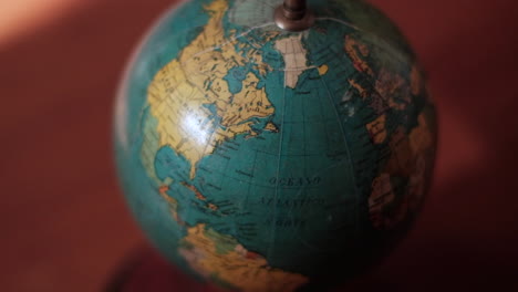 vintage globe spinning on axis in dimly lit room focus on north america