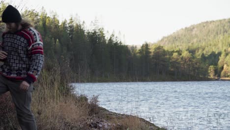 norwegian guy holding a binocular telescope walking by the lakeshore