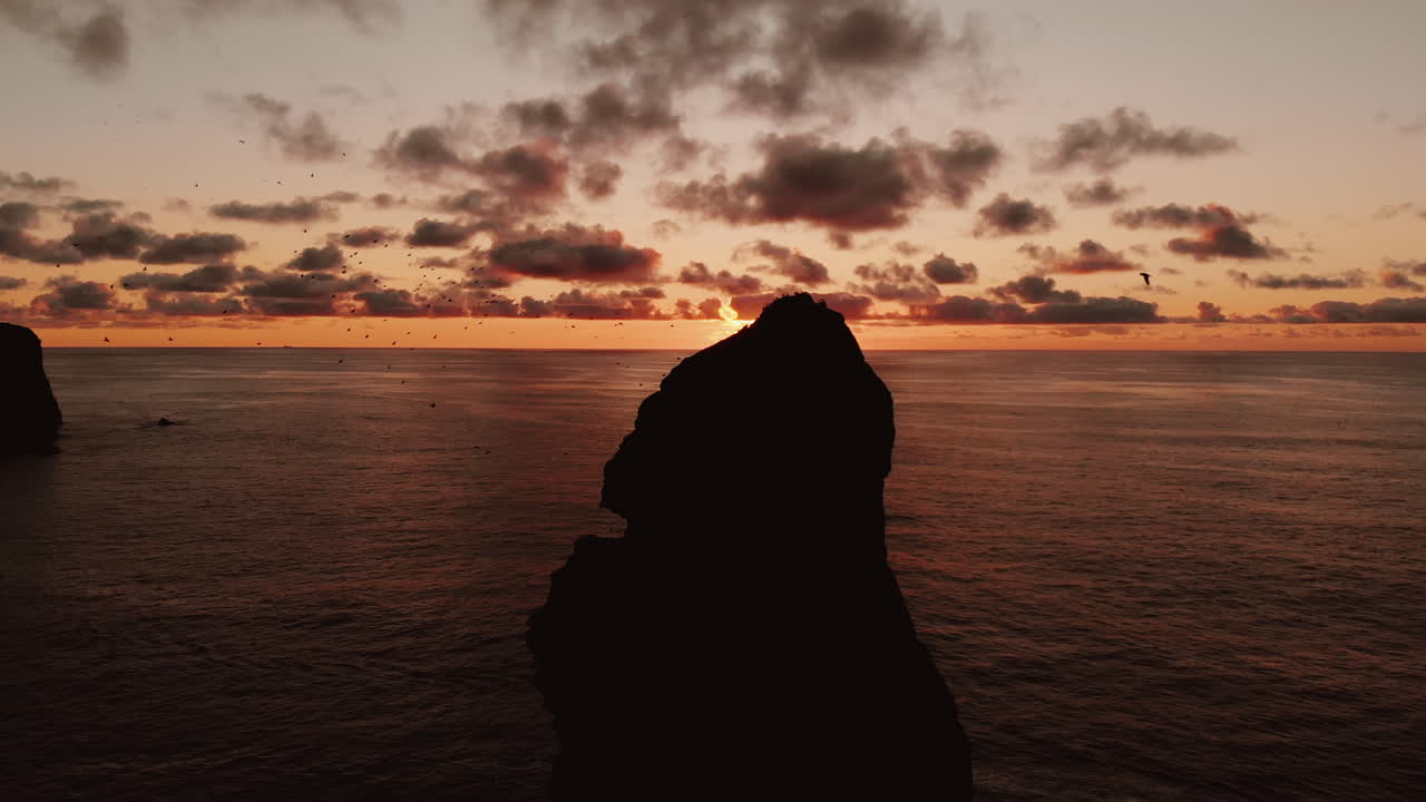 Dramatic Sunset Over Coastal Rock Formation with Birds