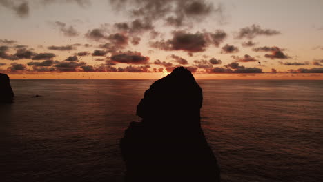 dramatic sunset over coastal rock formation with birds
