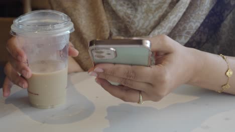woman using phone while enjoying a beverage