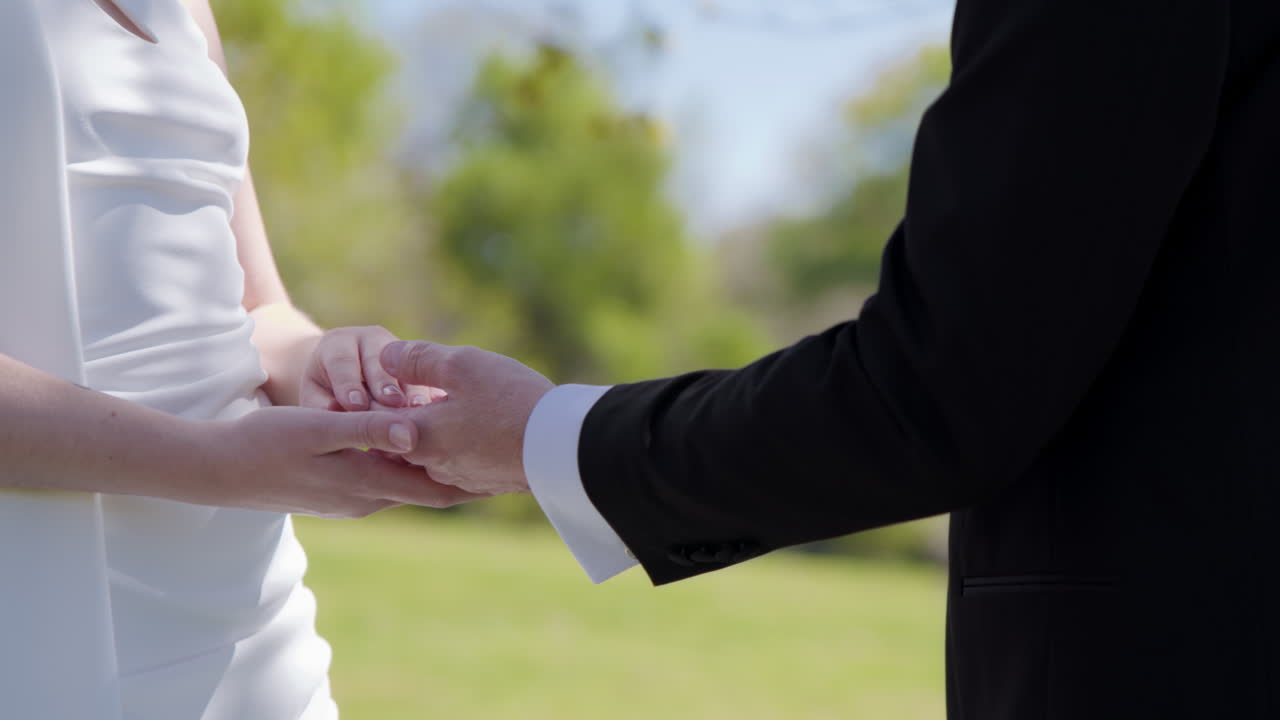 Husband putting wedding ring on wife finger, close up side view