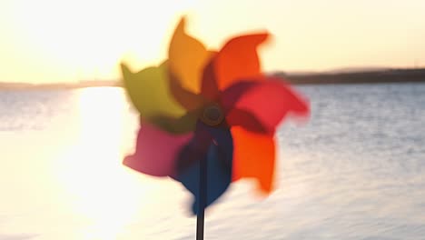 girar rodillo de plástico girar con un viento soplando se encuentra en la arena junto al mar contra la superficie lisa del mar y una puesta de sol rosada brillante molino de juguetes en la playa gran disco del sol espacio de copia