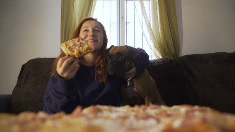 woman and boxer dog eating pizza on couch