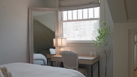 medium shot of a desk next to a window with a modern plant and mirror in a bedroom