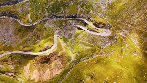 Wavy dangerous road in the spectacular mountains. Cars move slowly by the highway Transfagarash in Romania. Aerial view