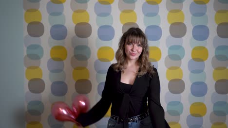 young woman dancing and holding balloons in hand against colorful background