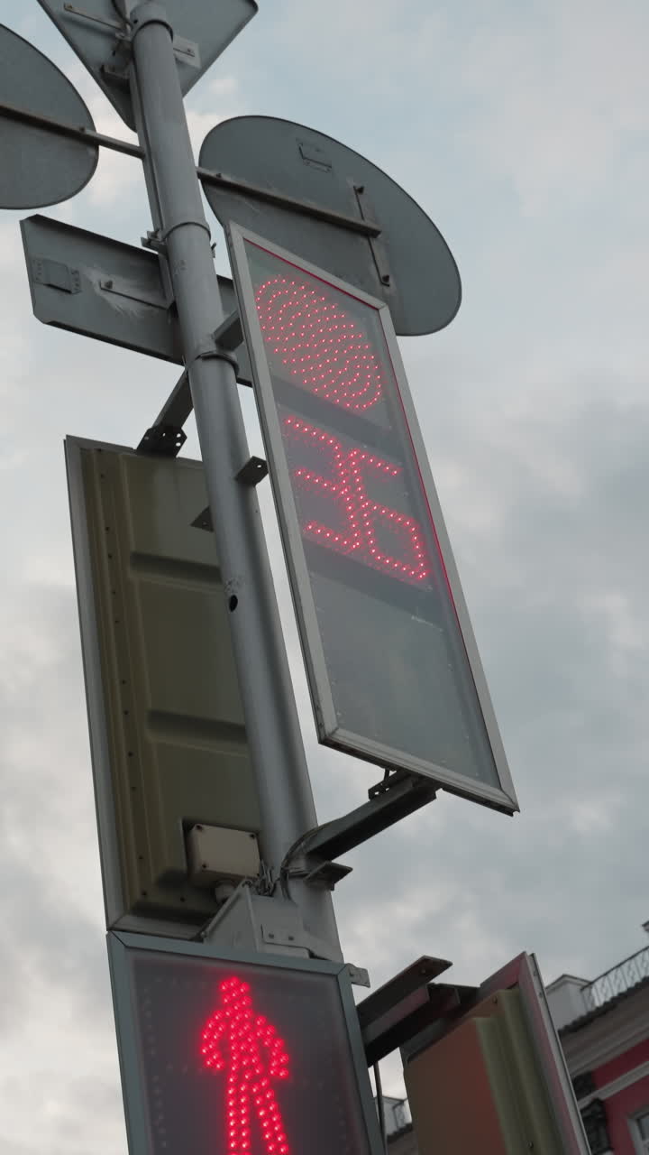 vista cercana de una señal de cruce de peatones con una frontera amarilla de neón y un semáforo digital que muestra una cuenta atrás, con un edificio pintado de rojo por el lado