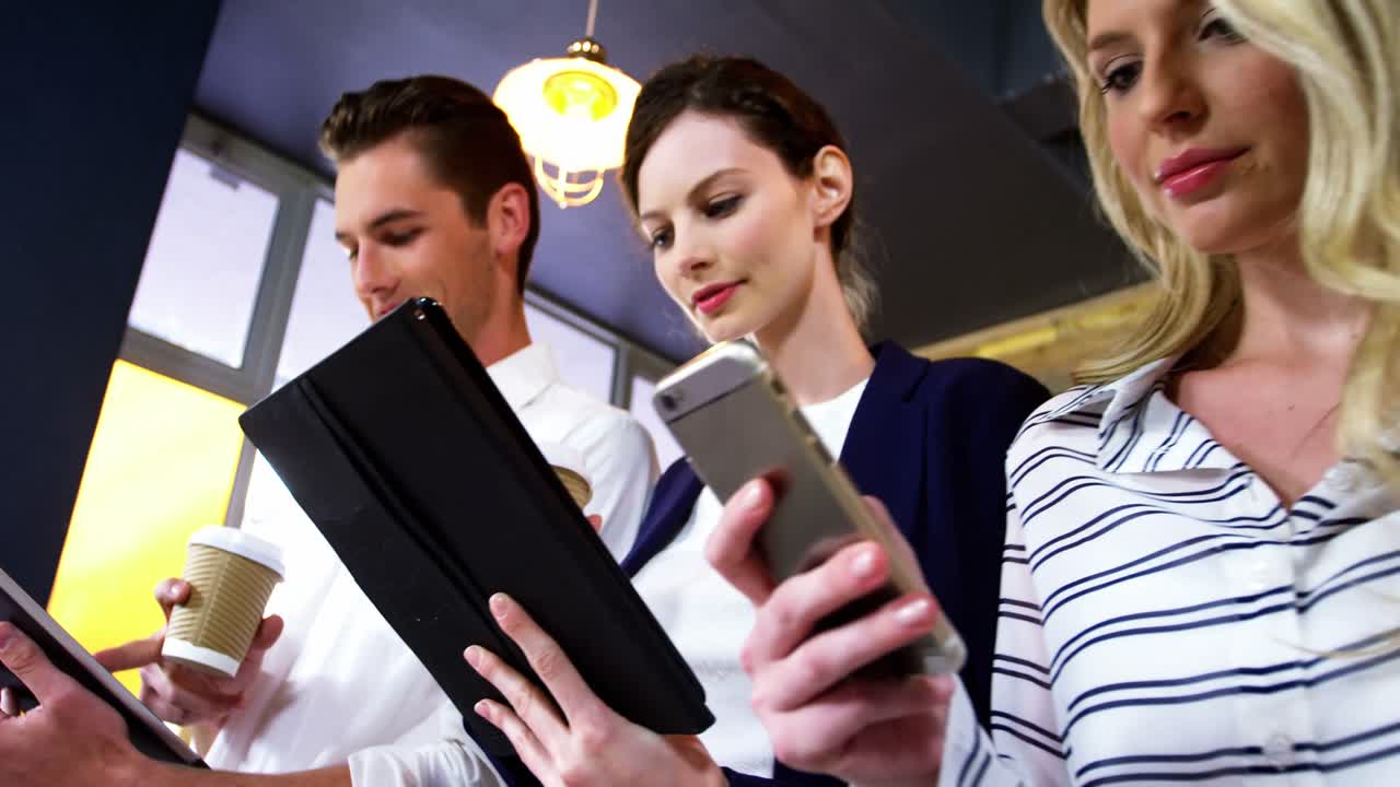 grupo de amigos que usan teléfonos móviles y tabletas digitales mientras toman una taza de café