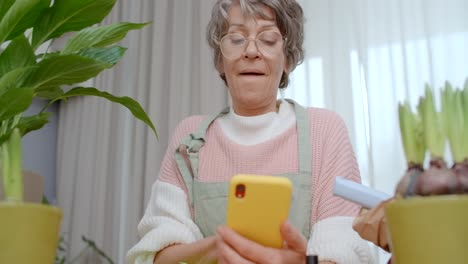 senior woman looking at her phone while gardening