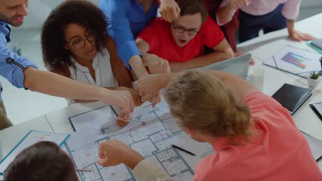 top view joyful colleagues stacking hands in conference room