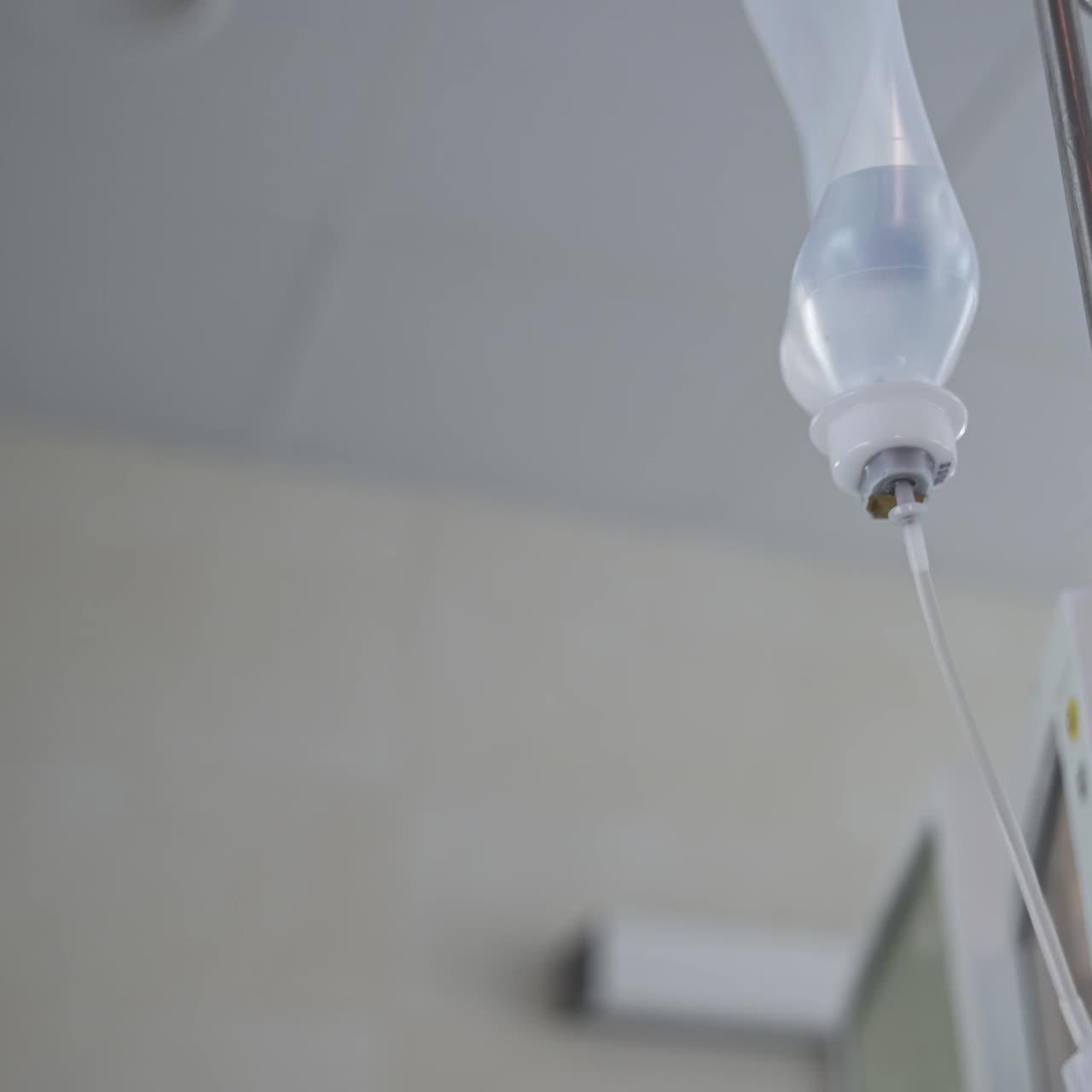 Una dottoressa con mascherina, cuffia e occhiali aggiusta la bottiglia con le medicine al flebo. Routine di sala operatoria. Vista dal basso
