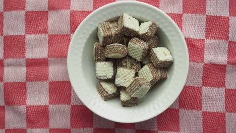 chocolate wafers in a white bowl on checkered tablecloth