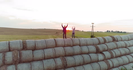 agriculture successful farmers standing on the top of a bale of straw