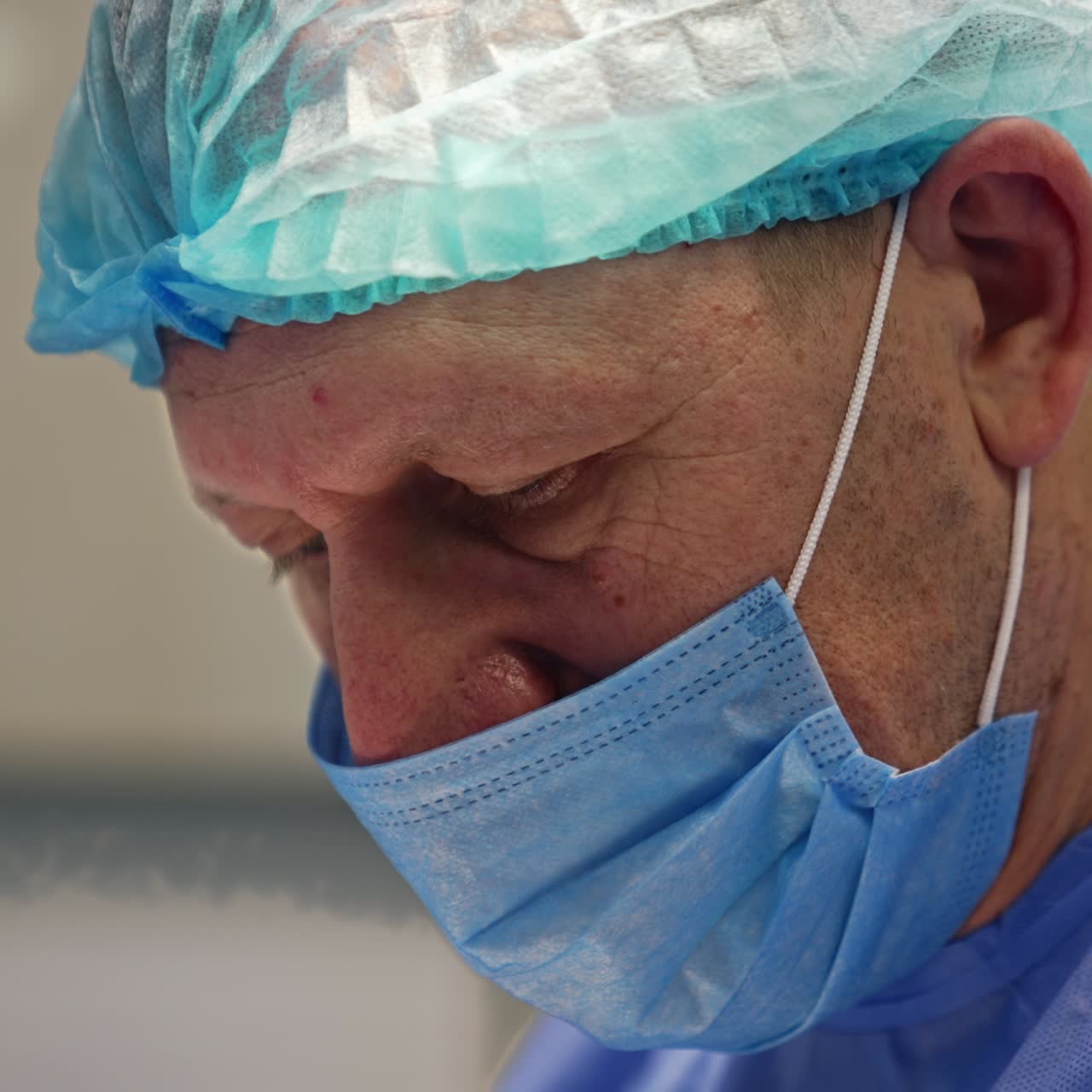 Adult male surgeon in mask and cap. Portrait of a doctor working at surgical procedure. Close up