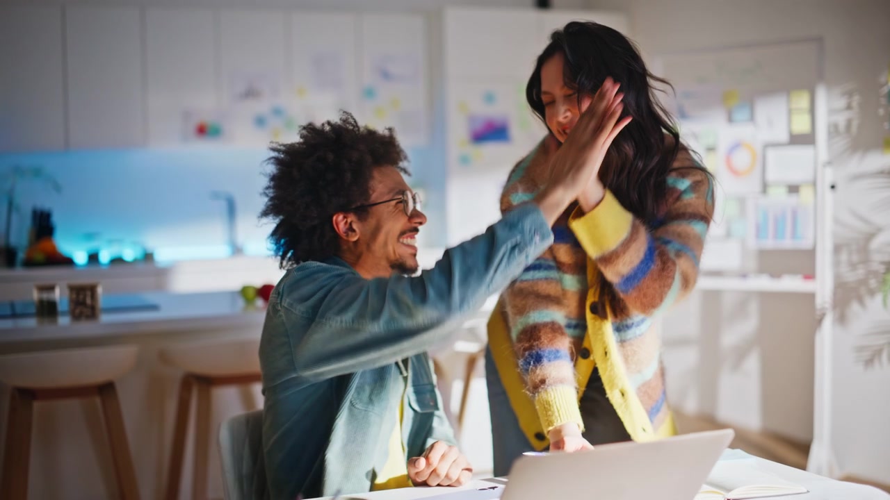 Coworkers high five celebrating success creative office. Man phone call laptop.